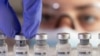 FILE - A woman holds vials labelled "COVID-19 Coronavirus Vaccine" over dry ice in this illustration created December 5, 2020.