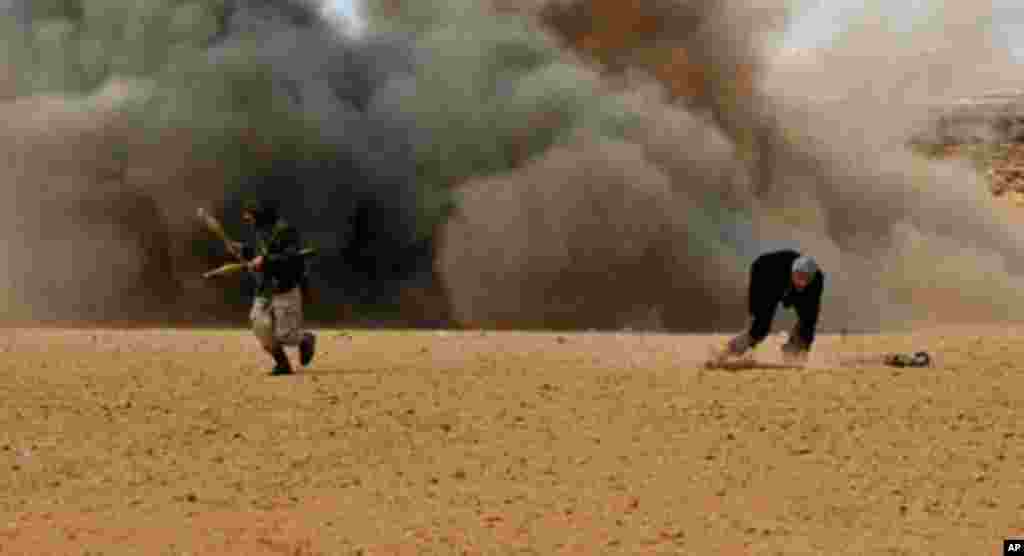 Libyan rebel fighters run for cover as shells explode nearby during a battle with forces loyal to leader Moammer Gadhafi, just few kilometers outside the oil town of Ras Lanuf, March 9, 2011