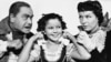 Actress Shirley Temple seems pleased but rather deafened by the din set up by her human "dog and cat" as they surround her during filming of Shirley's movie, "The Blue Bird." 