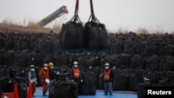 Công nhân di chuyển túi nhựa lớn màu đen có chứa bức xạ đất, lá cây và rác từ các hoạt động khử trùng tại khu vực lưu trữ tạm thời ở thị trấn Tomioka, tỉnh Fukushima.