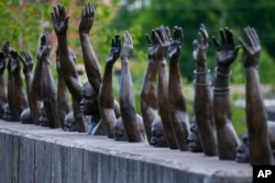 This photo shows a bronze statue called "Raise Up", part of the display at the National Memorial for Peace and Justice, a new memorial to honor thousands of people killed in lynchings