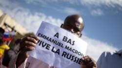 A man holds up a sign reading "Down with Emmanuel Macron, long live Russia" during a mass demonstration in Bamako, Jan. 14, 2022, to protest against sanctions imposed on Mali and the junta by the Economic Community of West African States (ECOWAS).