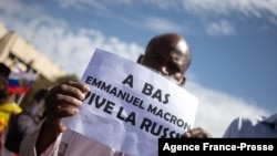 A man holds up a sign reading 'Down with Emmanuel Macron, long live Russia' during a mass demonstration in Bamako, Jan. 14, 2022, to protest against sanctions imposed on Mali and the junta by the Economic Community of West African States (ECOWAS).