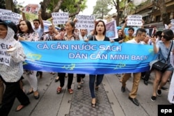 FILE - Vietnamese protesters hold a banner reading “Fish need clean water. People need the truth” during a rally denouncing recent mass fish deaths in Vietnam's central province, in Hanoi, Vietnam, May 1, 2016.