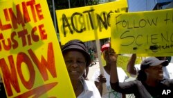 FILE - Demonstrator show their placards during climate change protest outside the Johannesburg Stock Exchange in Johannesburg, South Africa, Nov. 29, 2019. 