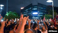 A group of people stage a protest outside the Hurriyet newspaper in Istanbul, Turkey, late Tuesday, Sept. 8, 2015.