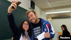 FILE - A couple takes a selfie while voting in Mataro, near Barcelona, Spain, Nov. 9, 2014. In the United States, various states are weighing whether to allow "I Voted" selfies in the ballot booth.