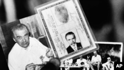 FILE - Federal police agent holds two photos and the identity card June 7, 1985 found in the house in which the man believed to be Nazi War Criminal Josef Mengele lived. Photo on left shows Mengele eating.