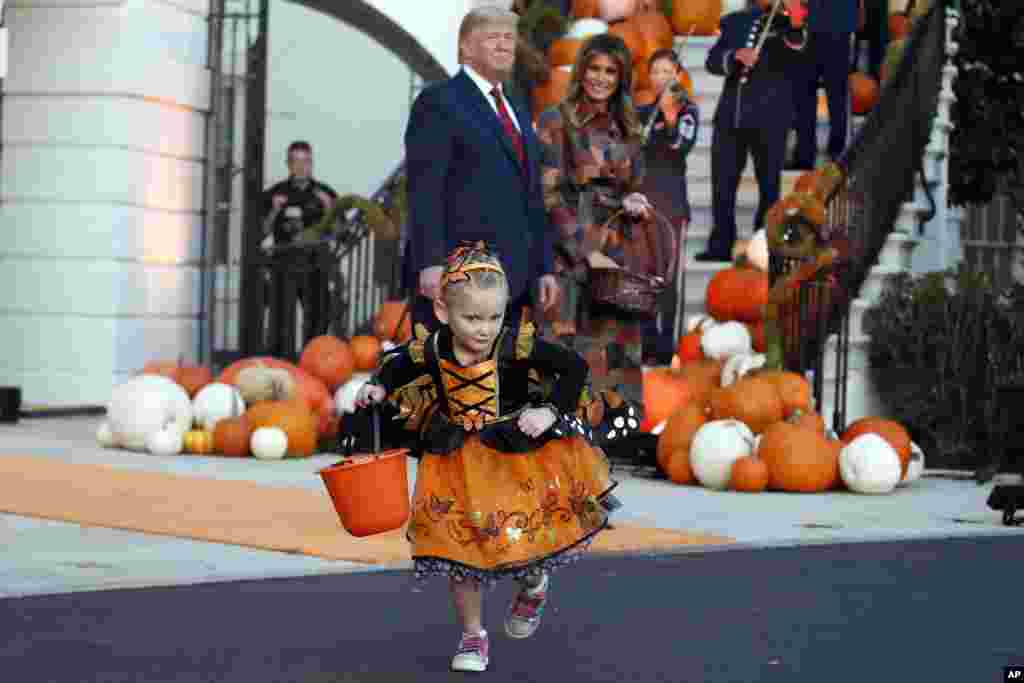 Presiden Donald Trump dan ibu negara Melania Trump mengamati seorang anak perempuan selama acara &quot;trick-or-treat&quot; Halloween (pembagian permen kepada anak-anak) di halaman selatan Gedung Putih di Washington DC.