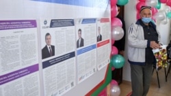 A voter walks near a board displaying information about candidates, including Uzbek incumbent President Shavkat Mirziyoyev, at a polling station during a presidential election in Tashkent, Oct. 24, 2021.