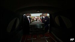 Mortician Cordarial O. Holloway, foreground left, funeral director Robert L. Albritten, foreground right, and funeral attendants Eddie Keith, background left, and Ronald Costello place a casket into a hearse on April 18, 2020, in Dawson, Ga. 