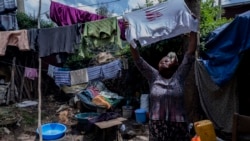 Mother of two Amsale Hailemariam, a domestic worker who lost work because of the coronavirus, hangs clothes after washing them outside her small tent in the capital Addis Ababa, Ethiopia on Friday, June 26, 2020. (AP Photo/Mulugeta Ayene)