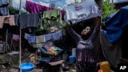 Mother of two Amsale Hailemariam, a domestic worker who lost work because of the coronavirus, hangs clothes after washing them outside her small tent in the capital Addis Ababa, Ethiopia on Friday, June 26, 2020. (AP Photo/Mulugeta Ayene)