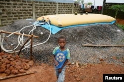 FILE - A boy walks past a water supply point at an internally displaced persons camp in Regent, Sierra Leone. Aug. 21, 2017.
