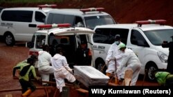  Pekerja yang mengenakan pakaian pelindung mengubur peti mati di area pemakaman yang disediakan pemerintah untuk korban Covid-19. (Foto: REUTERS/Willy Kurniawan)