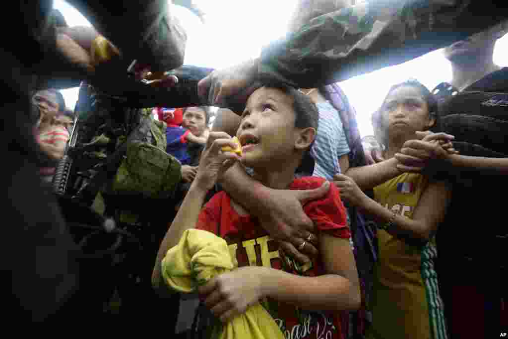 A Philippine air force officer hands out orange slices to typhoon survivors as they line up to board a C-130 military transport plane in Tacloban city, Nov. 12, 2013. 