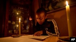 FILE - Ndofhiwa Mabasa, studying by candle light to prepare for her national senior certificate examinations as load shedding hits stage 3 in Vosloorus township, east of Johannesburg, South Africa, Thursday, Oct. 28, 2021.