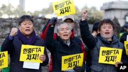 South Korean protesters from a farmers' group shout slogans during a rally denouncing the Free Trade Agreement (FTA) between South Korea and China in front of the National Assembly in Seoul, South Korea, Monday, Nov. 30, 2015.