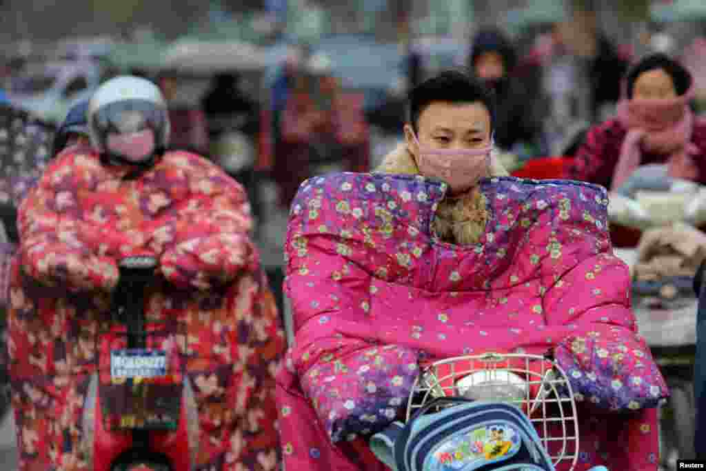 Para pengendara mengenakan jaket khusus untuk melawan udara dingin di Lianyungang, Jiangsu, China.