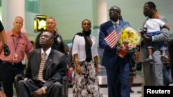 Mariam Ishag (Mariam Yahya Ibrahim) arrives at the airport in Manchester, New Hampshire with family members, including her husband Daniel Wani (L) and his brother Gabriel Wani (R), July 31, 2014.