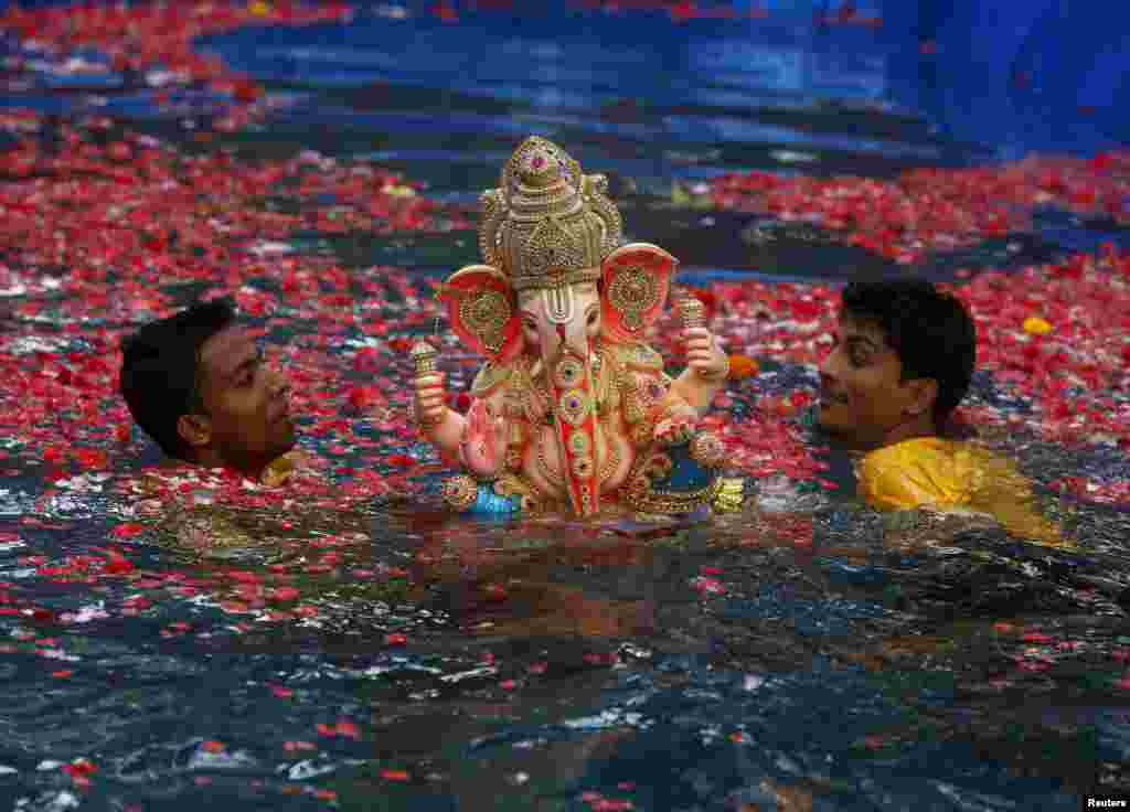 Những tình nguyện viên mang đầu tượng của thần voi thần Ganesh của đạo Hindu, vị thần của sự thịnh vượng, ngâm xuống một cái ao trong lễ hội Ganesh Chaturthi kéo dài 10 ngày ở thành phố Mumbai, Ấn Độ.