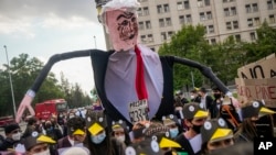 Estudiantes universitarios disfrazados de pingüinos llevan una maqueta del presidente chileno Sebastián Piñera mientras se manifiestan contra el efecto de un potencial proyecto minero, frente al palacio presidencial de La Moneda en Santiago, Chile, en octubre de 2021.