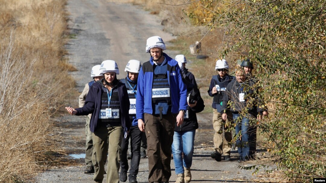 Members of the Organization for Security and Cooperation in Europe (OSCE) Special Monitoring Mission to Ukraine walk along a road as they arrive for monitoring ahead of the proposed withdrawal of troops, in the village of Petrovskoye in Donetsk region, Uk