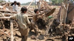 Men digging up the remains of their home in the Azakhel refugee camp, near Peshawar, following the floods that have left much of Pakistan in misery, Aug 2010