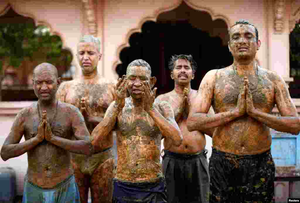 People pray after applying cow dung on their bodies during &quot;cow dung therapy&quot;, believing it will boost their immunity to defend against the COVID-19 at a cow shelter on the outskirts of Ahmedabad, India.