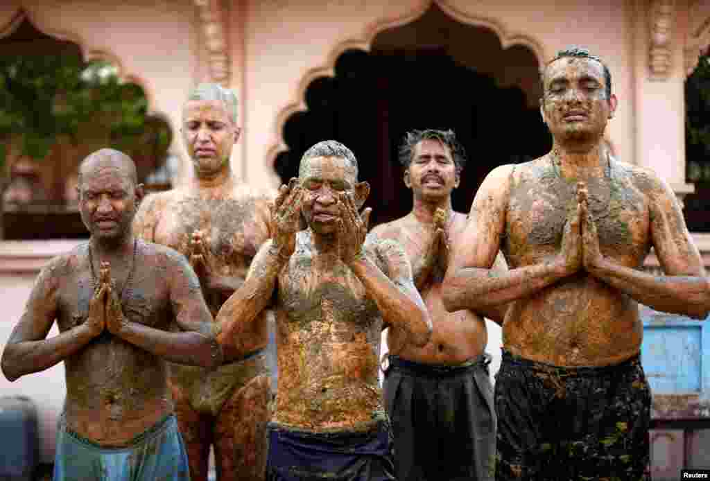 People pray after applying cow dung on their bodies during &quot;cow dung therapy&quot;, believing it will boost their immunity to defend against the COVID-19 at the Shree Swaminarayan Gurukul Vishwavidya Pratishthanam Gaushala or cow shelter on the outskirts of Ahmedabad, India.