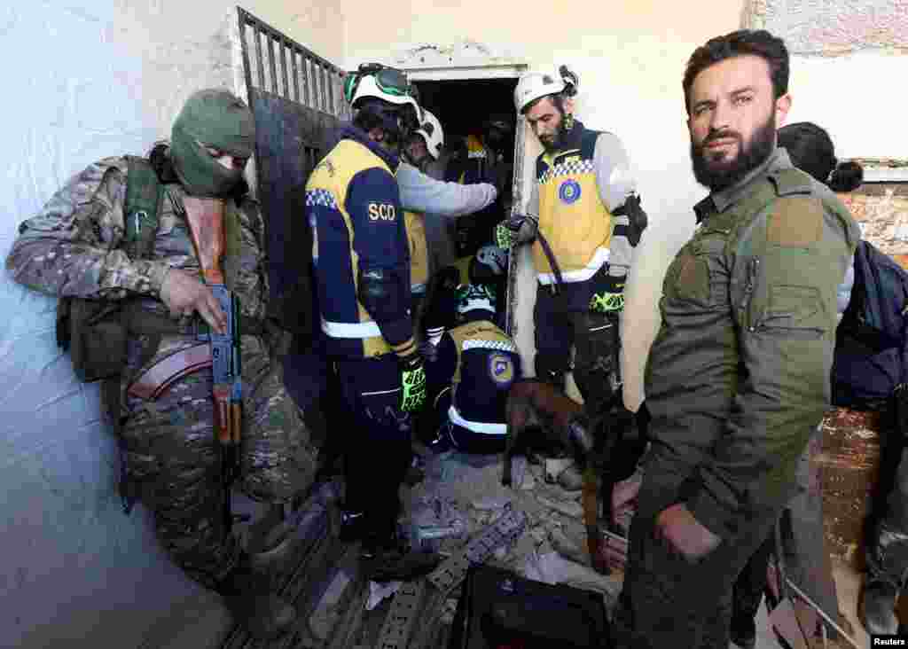 Members of the Syrian civil defense group, known as the White Helmets, search for prisoners at Sednaya prison, with rebel fighters around, in Sednaya, Dec.9, 2024.