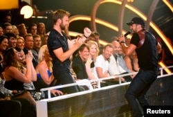 Luke Bryan performs "Kick the Dust Up" as Charles Kelley (L) of Lady Antebellum dances during the 2015 CMT Awards in Nashville, Tennessee June 10, 2015.