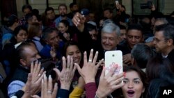 A woman takes a selfie backdropped with presidential hopeful Andres Manuel Lopez Obrador during a pre-campaign rally in Mexico City, Dec. 15, 2017. On Feb. 7, 2018, reports say Lopez Obrador has an 11-point lead over rivals, according to an opinion poll completed last week.