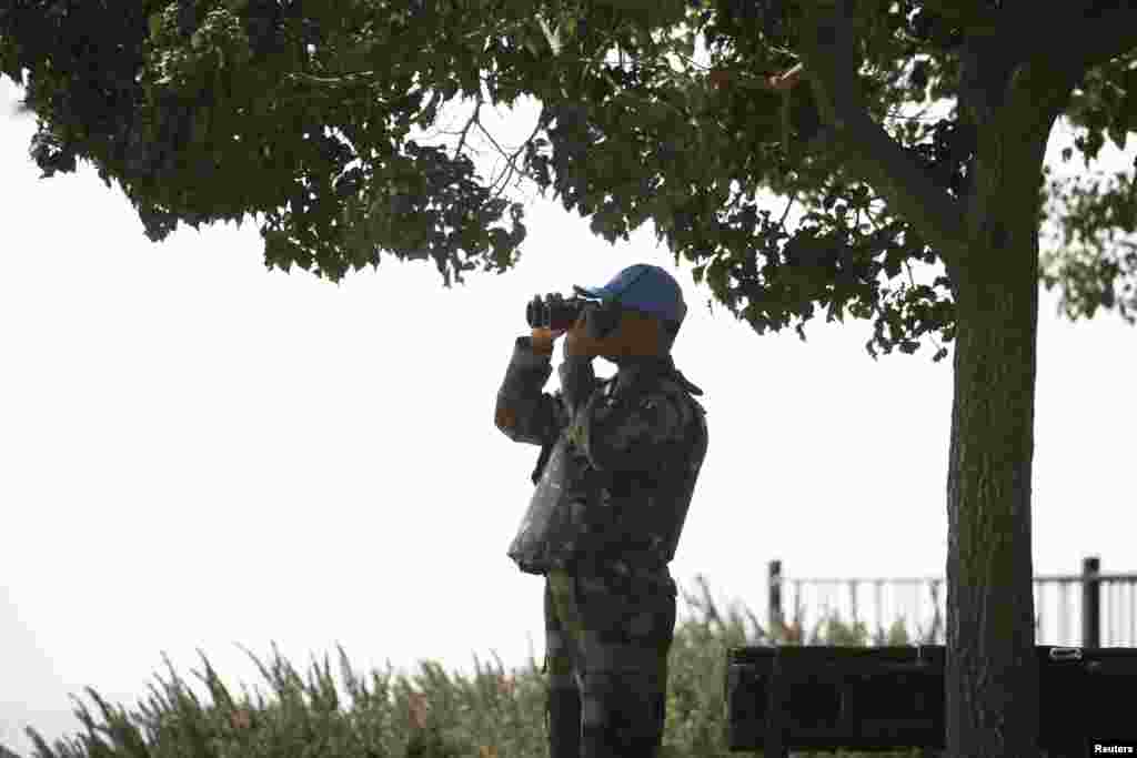 A member of the U.N. Disengagement Observer Force looks through binoculars at the Syrian side of the Qunietra crossing from the Israeli-occupied Golan Heights, Sept. 1, 2014.