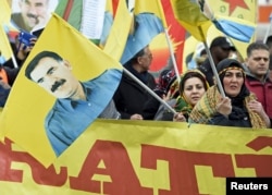 FILE - Pro-Kurdish demonstrators carry a flag showing Abdullah Ocalan, the jailed leader of the Kurdistan Workers' Party, as they protest against Turkish authorities during the spring festival of Newroz celebrations in downtown Hannover, Germany, March 19, 2016.