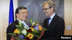 European Commission President Jose Manuel Barroso (L) receives flowers from Atle Leikvoll, Norway's Ambassador to the European Union, at the EC headquarters in Brussels October 12, 2012.