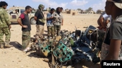 FILE - Libyans gather around the remains of a helicopter that crashed near Benghazi, Libya, July 20, 2016.