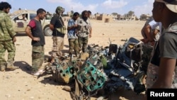 Libyans gather around the remains of a helicopter that crashed near Benghazi, Libya, July 20, 2016.