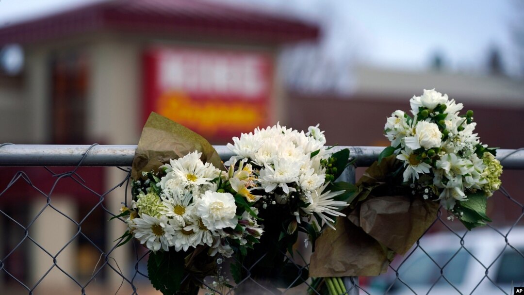Bouquets line a fence put up around the parking lot where a mass shooting took place the day before in a King Soopers grocery store, March 23, 2021, in Boulder, Colo.