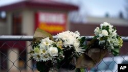 Bouquets line a fence put up around the parking lot where a mass shooting took place the day before in a King Soopers grocery store, March 23, 2021, in Boulder, Colo.