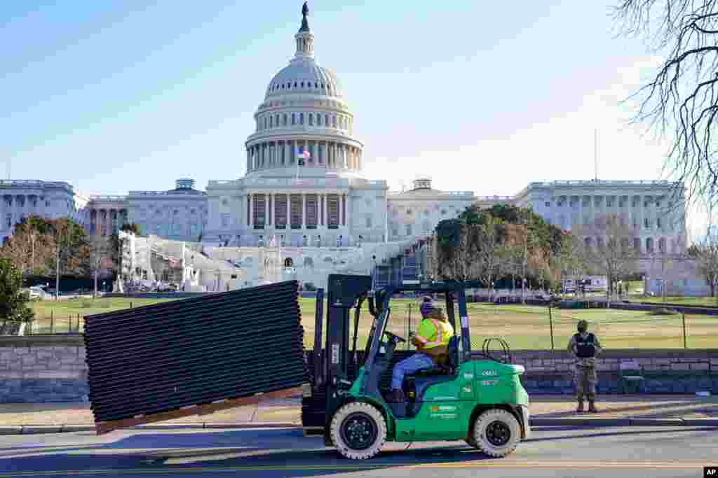 Workers place security fencing in place outside the mostly quiet Capitol in Washington, D.C.
