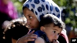 Syrian refugee girl carries her sister, at camp in Ketermaya village, southeast of Beirut, March 14, 2013.