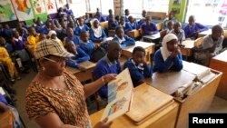 FILE - Helen Mashele from South Africa reads the biography of former South African president Nelson Mandela to pupils at Kilimani Primary School in Kenya's capital Nairobi, July 18, 2013.