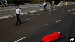 People walk to work as a protester sleeps on a main road in the occupied areas in Central district, Hong Kong, Oct. 9, 2014. 