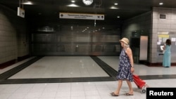 A commuter walks by a closed train station in a northern Athens suburb July 16, 2013. Some central Metro stations remained closed after a police order for safety reasons during a general 24-hour strike in Greece.