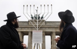 FILE - Clergymen look at a Menorah to be lit for the Jewish holiday of Hanukkah in December 2008 at the Brandenburg Gate in Berlin, Germany. (AP Photo/Franka Bruns)