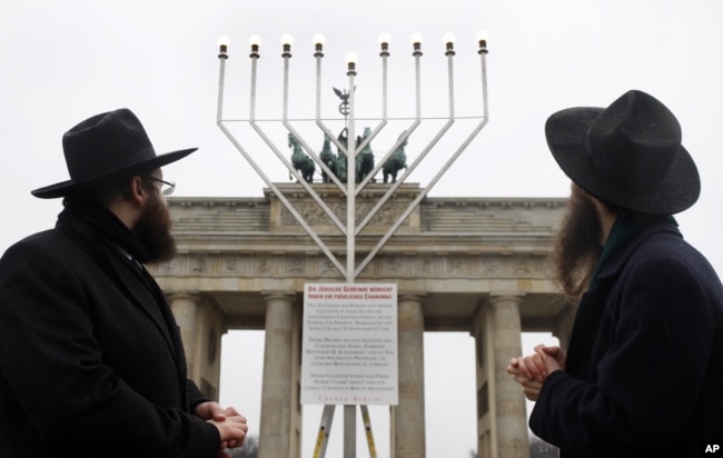 FILE - Clergymen look at a Menorah to be lit for the Jewish holiday of Hanukkah in December 2008 at the Brandenburg Gate in Berlin, Germany. (AP Photo/Franka Bruns)