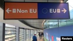 FILE - Passengers walk past a sign directing them to specific lines for EU and non-EU passports as they arrive at Dublin Airport in Ireland, Sept. 6, 2019.