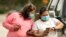 FILE -- Women wear masks as they check a mobile phone in Houston, Texas.