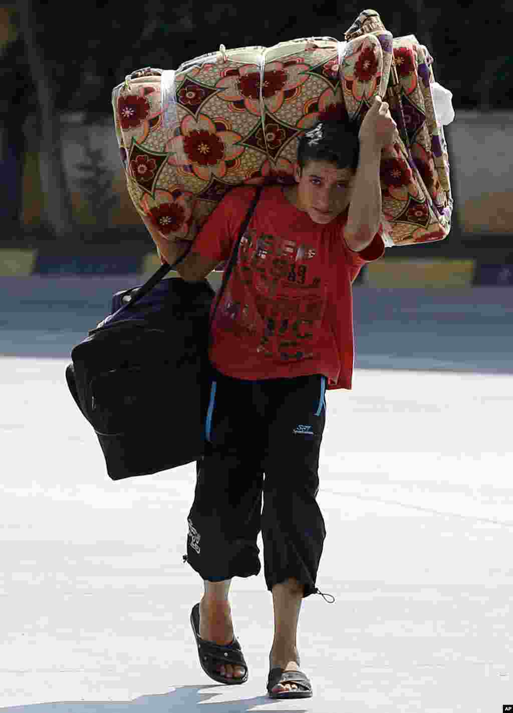 A Syrian boy carries his belongings as he passes through the Turkish Cilvegozu gate border with Syria, August 30, 2013. 